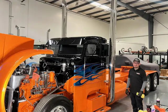 Highline Auto Care technician beside a polished orange show Peterbilt with chrome stacks in San Jose